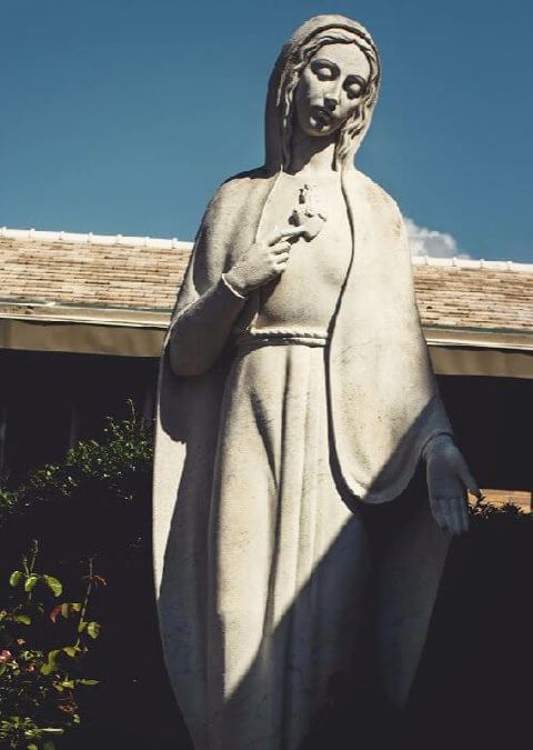 Une statue de la mère Marie dans un jardin.