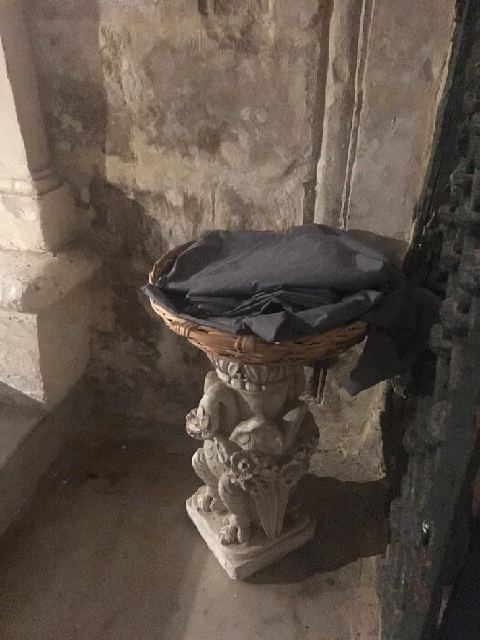 Un panier sur un socle de pierre contenant des châles pour couvrir la peau dans la grotte de saint Paul.